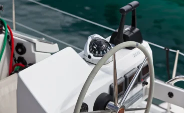 boat-steering-wheel-and-compass-on-the-ocean-2026-03-16-04-30-32-utc A boat steering wheel with cables