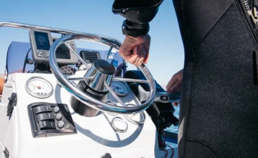 boating-on-sunny-day-with-wetsuit-at-helm-2026-03-09-23-14-30-utc A close up of a boat helm with some basic marine electronics