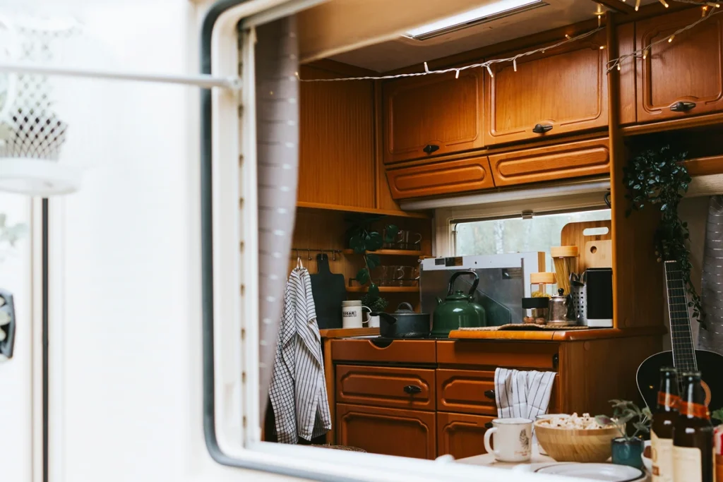 A caravan kitchen thorugh a window, with a stove and cooking utensils, two caravan must-haves