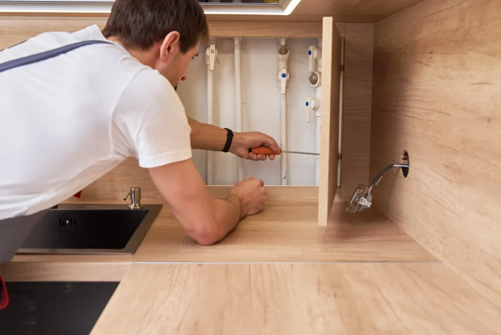 A man repairing caravan pipes with plumbing repair tools - a caravan must-have
