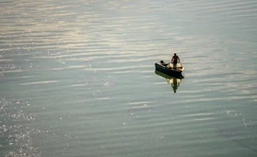 morning-silence-fishing-on-a-big-river-2026-01-09-14-27-03-utc A person fishes on a boat, their rod attached to the stern